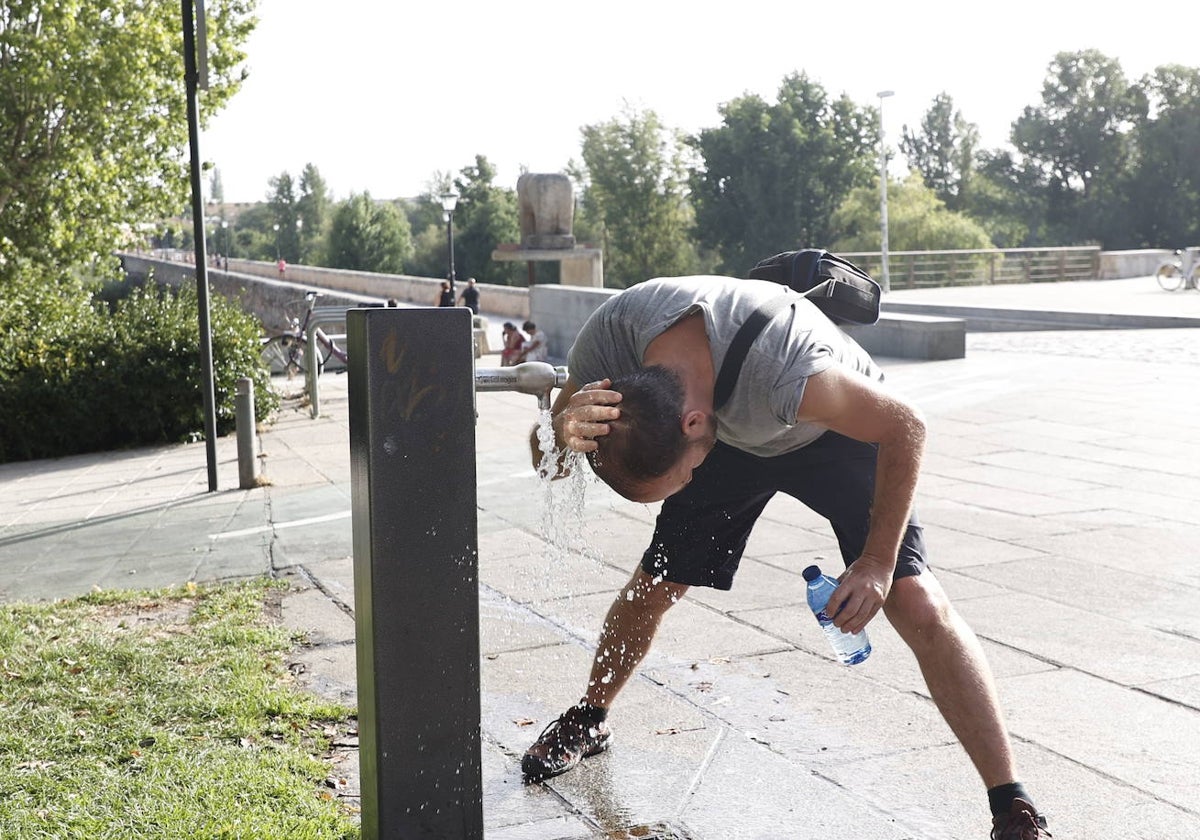 Un hombre se refresca en una fuente de Salamanca