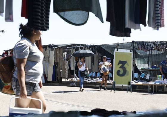 Una mujer se cubre del sol con un paraguas en el rastro de Salamanca.