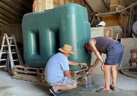 Dos vecinos cogen agua en un pueblo en un depósito.