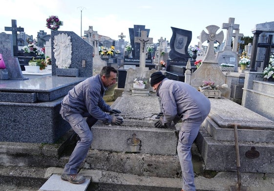 Dos trabajadores del cementerio colocando una lápida.