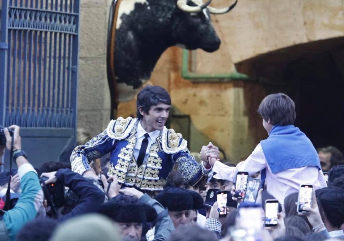 Castella saluda a un niño mientras sale en hombros de La Glorieta.