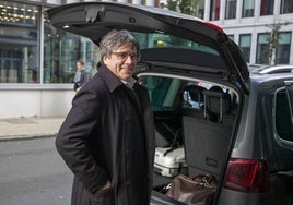 Puigdemont sonría delante del maletero de un coche.