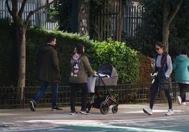 Una pareja pasea junto a su bebé por la ciudad.