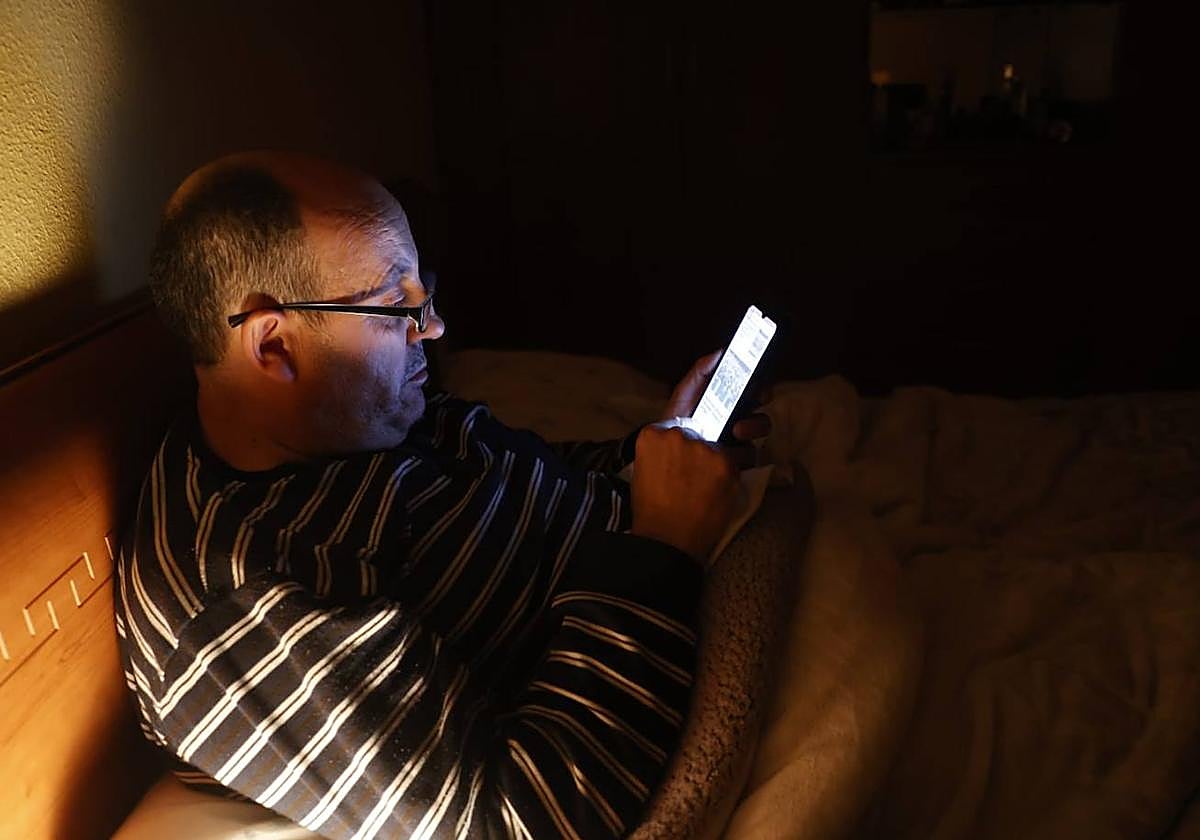 Un salmantino consulta su teléfono móvil desde la cama.