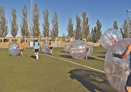 Jóvenes practicando un juego con 'burbujas' en el campo de fútbol de Carbajosa.