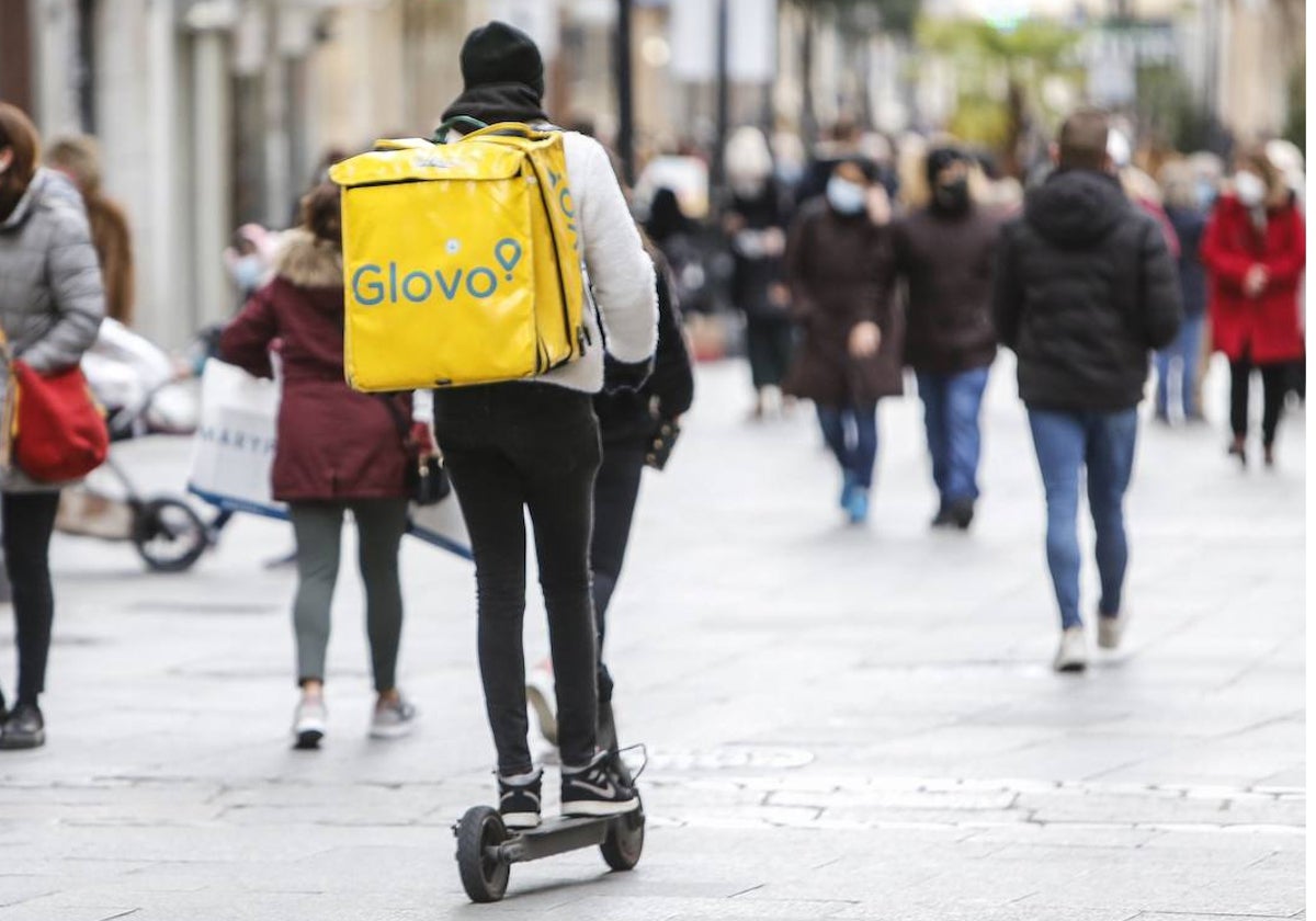 Un repartidor circula en patinete por una calle céntrica de la ciudad.