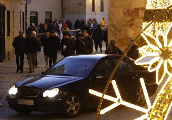 Un vehículo circula este miércoles entre público en la calle San Vicente Ferrer.