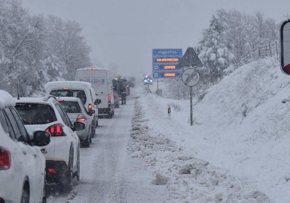 Una fila de coches parados en una carretera nevada