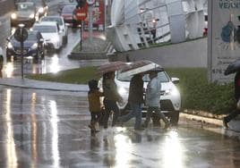 Varias personas caminan por la avenida de Portugal con paraguas por la lluvia.