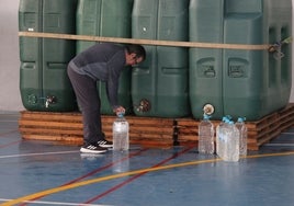 Un vecino recogiendo agua potable gratis de los depósitos instalados en el frontón cubierto de Santa Marta.