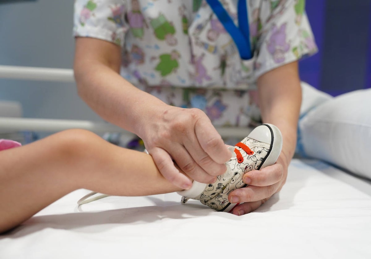 Una sanitaria de la UCI pediátrica de Salamanca viste a la pequeña.