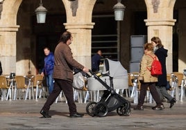 Un hombre empuja un carro de bebé por la Plaza Mayor.