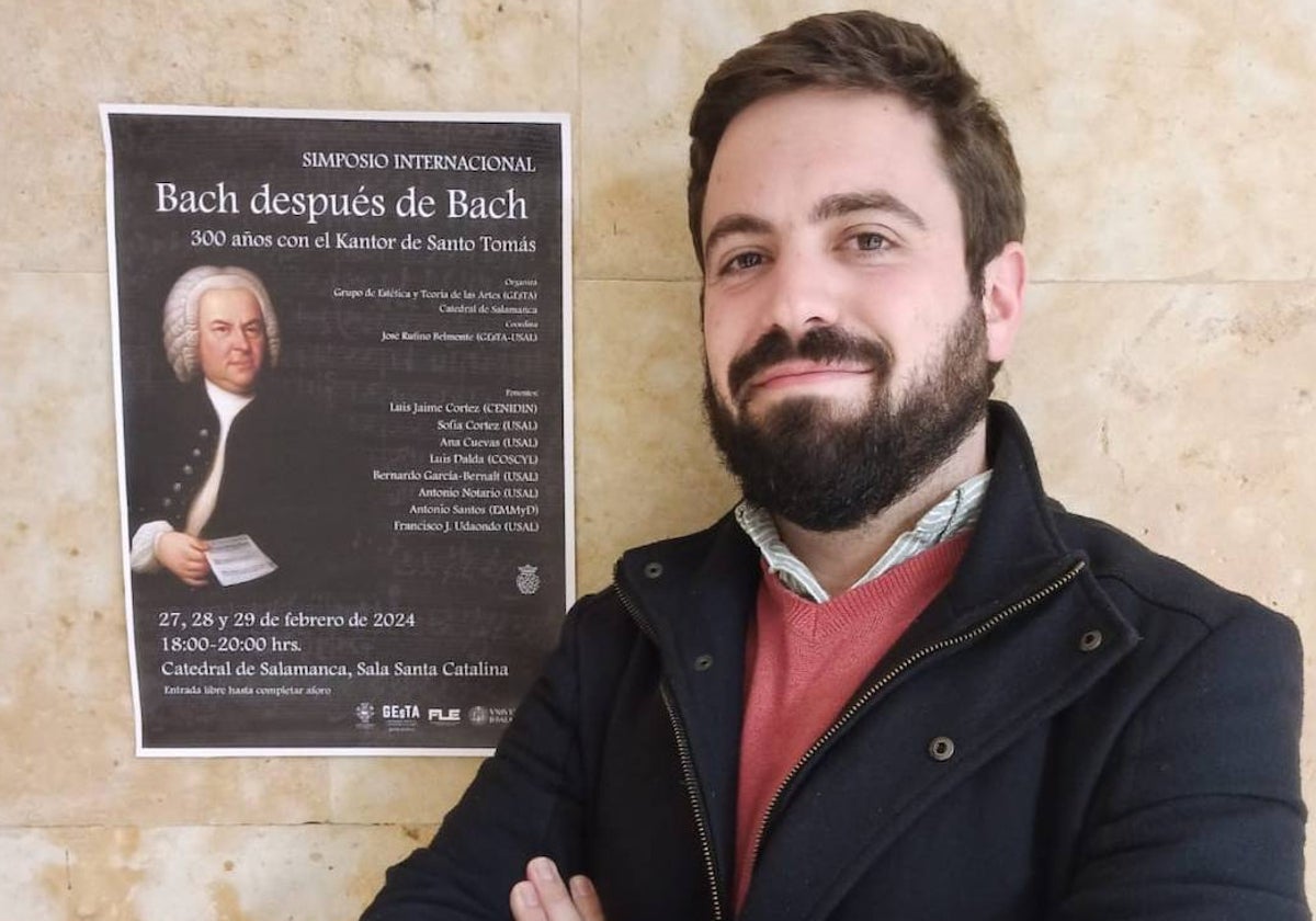 El investigador de la Facultad de Filosofía José Rufino Belmonte, junto al cartel del simposio.