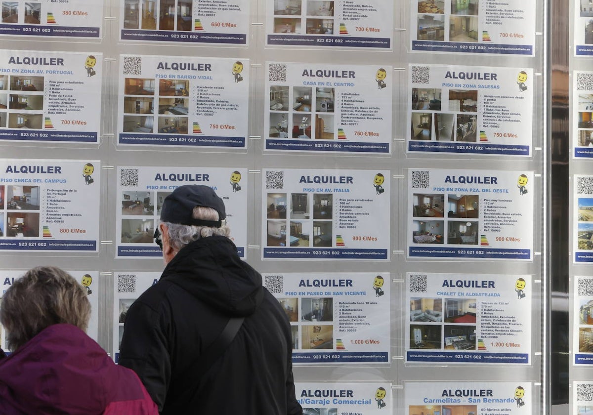 Una pareja observa los anuncios de pisos de alquiler en una inmobiliaria.