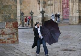 Una joven lucha con su paraguas contra el viento.