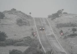 Un coche circula por la carretera durante este sábado bajo una intensa nevada.