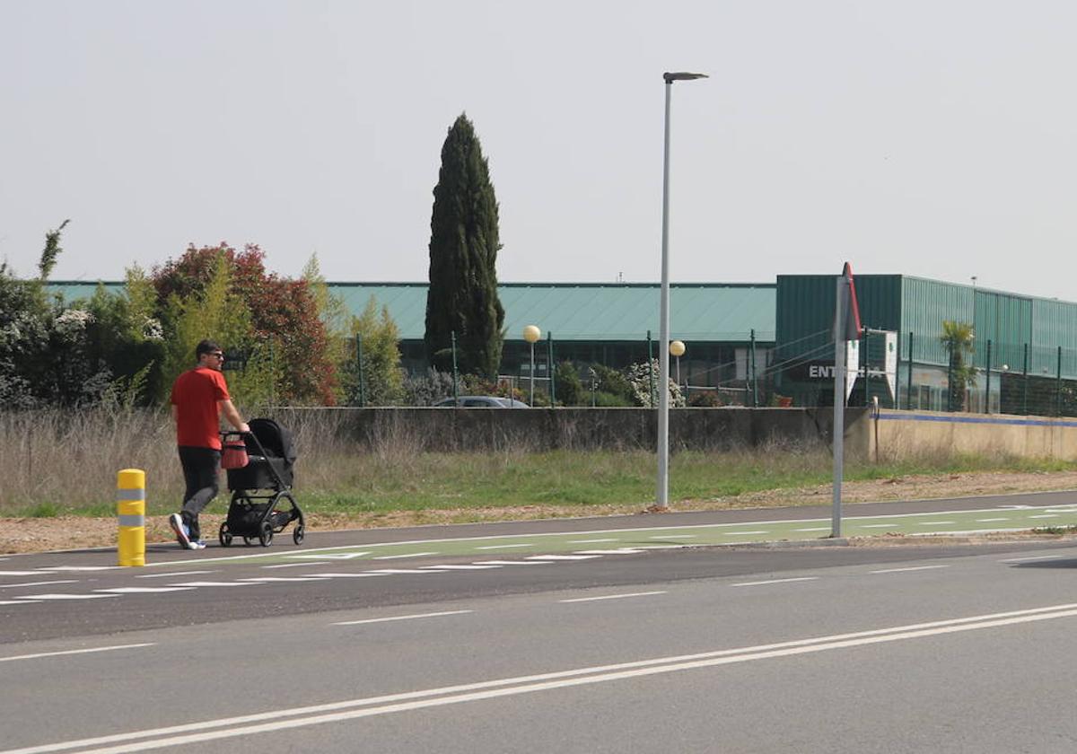 Un hombre pasea con un carrito de bebé por la zona peatonal del nuevo carril bici de Villamayor.