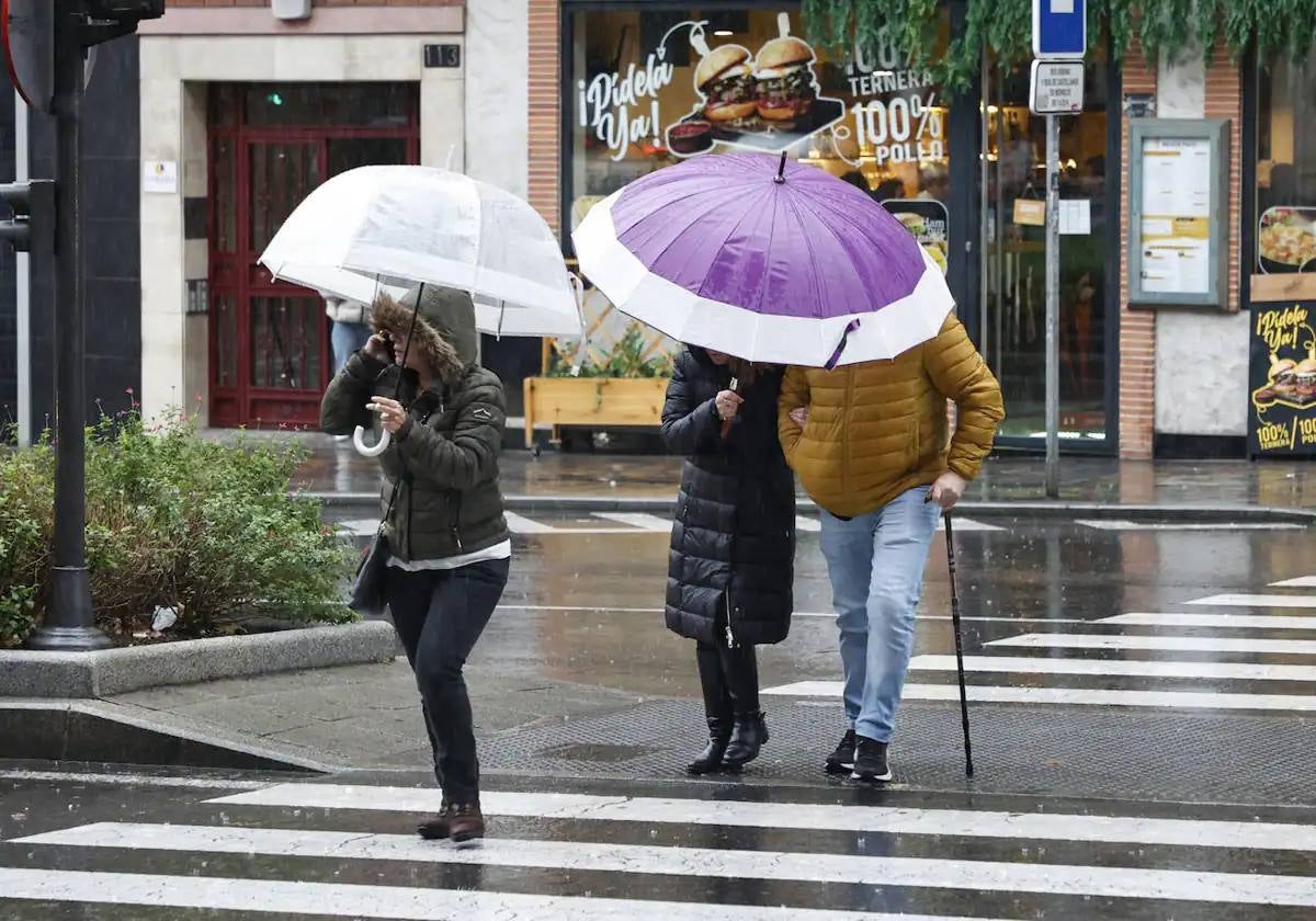 Un grupo de salmantinos cruza un paso de peatones en mitad de la lluvia.