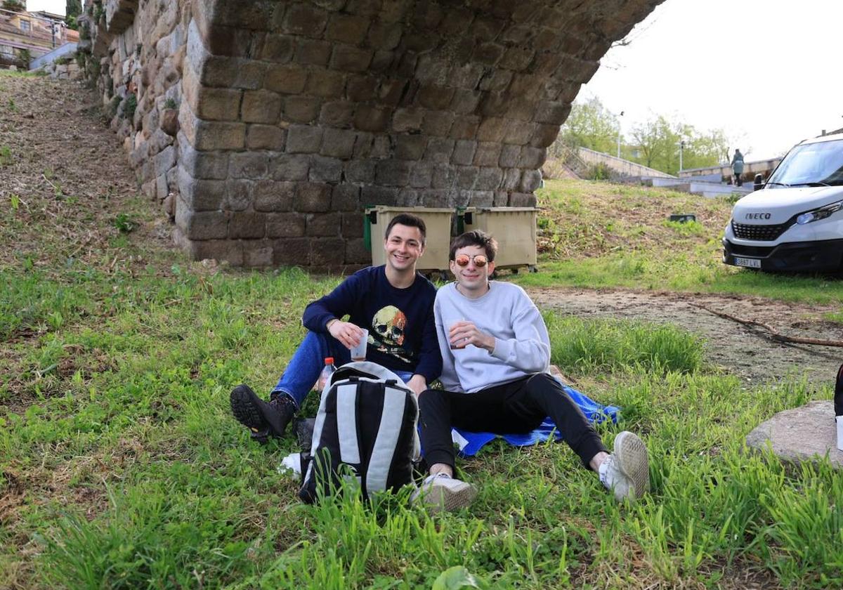 Dos jóvenes sentados en las orillas del Tormes a primera hora de la mañana de este lunes