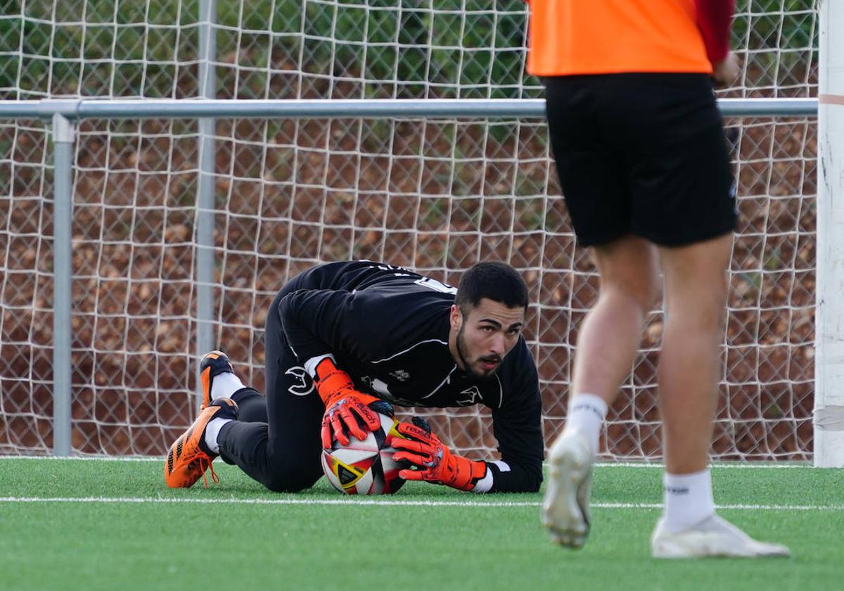 Iván Martínez bloca un balón entre las dos manos durante un entrenamiento en el anexo al Reina Sofía