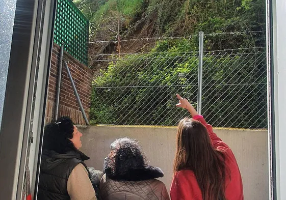 Tres vecinas de los edificios 9 y 11 de la calle Arco del Monte contemplando la parte del terraplén desprendida la semana pasada.