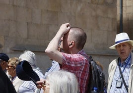 Un turista con gorra se protege del sol en la ciudad.