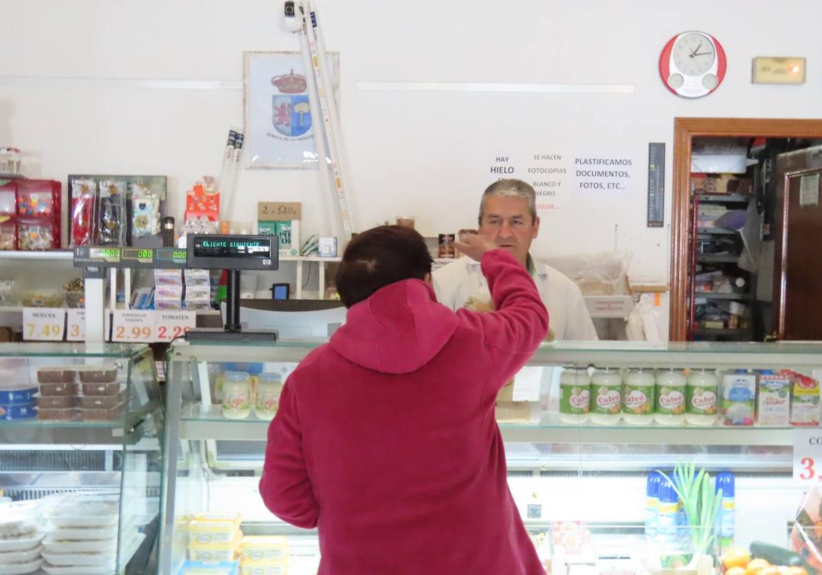 Pepe Galiano atiende a una clienta en su tienda de ultramarinos de Zorita de la Frontera.