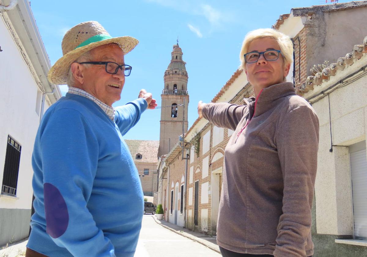 Los vecinos de Palaciosrubios, Quico Albarrán Vaquero y Clara María Vaquero, señalan la torre de la iglesia desde una céntrica calle de la localidad.