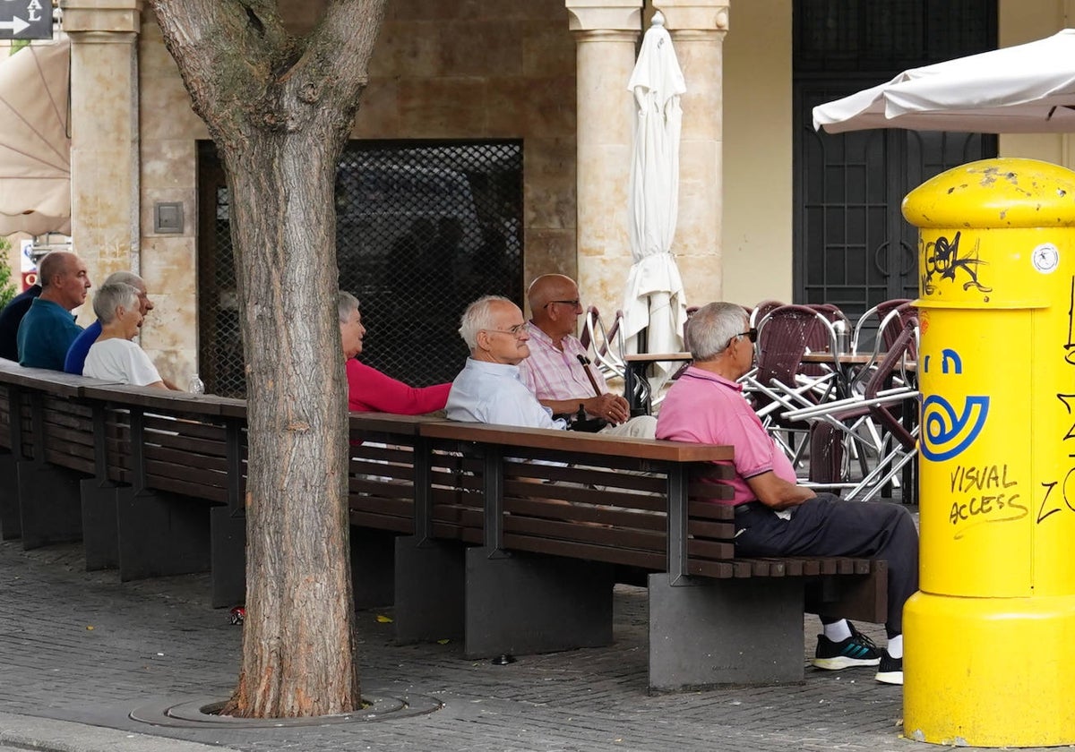 Mayores sentados en el banco de la plaza del Corrillo.