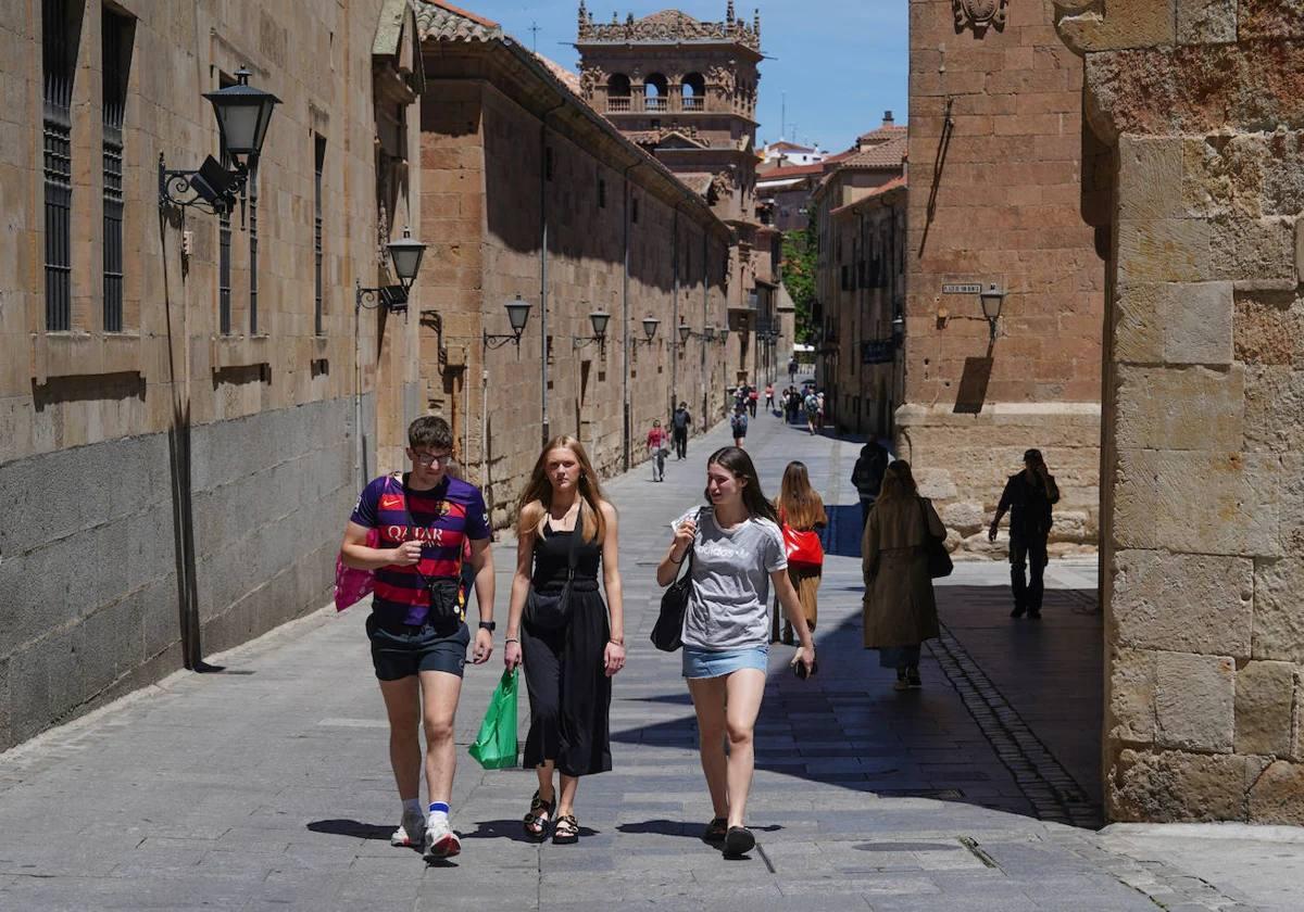 Tres jóvenes transitan por una de las calles más céntricas de Salamanca bajo el calor.