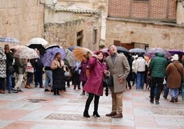 Numerosas personas observan monumentos en Salamanca bajo la lluvia.