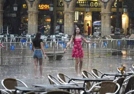 Dos chicas bailan en la Plaza Mayor bajo la lluvia.