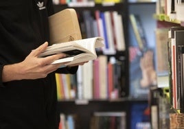 Un joven lee un libro en una biblioteca.