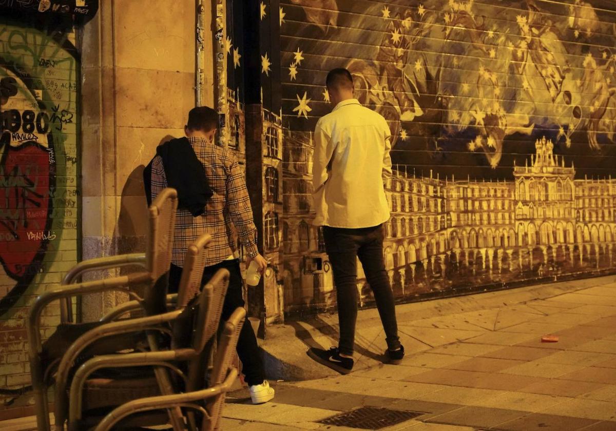 Dos jóvenes orinan contra una pared en el centro de la ciudad.