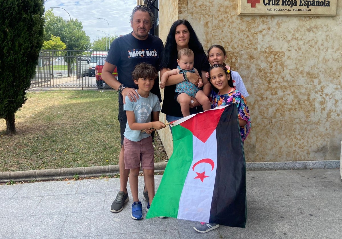 Lamina, de 10 años, posa junto a su familia y la bandera de su país.