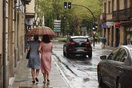 Mujeres bajo un paraguas resguardándose de una lluvia estival