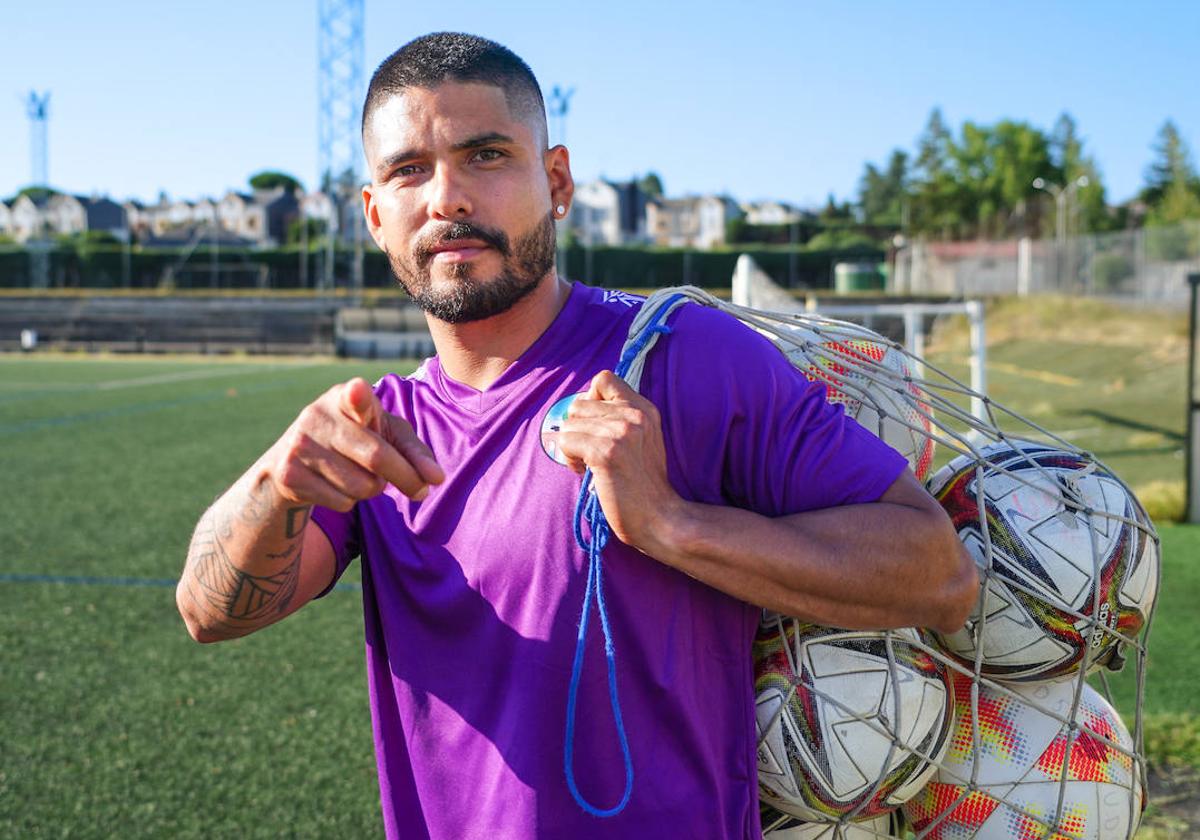 Martín Galván señala con su dedo índice a la cámara mientras carga una saca de balones.