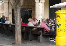 Un grupo de mayores en un banco de la plaza del Corrillo.