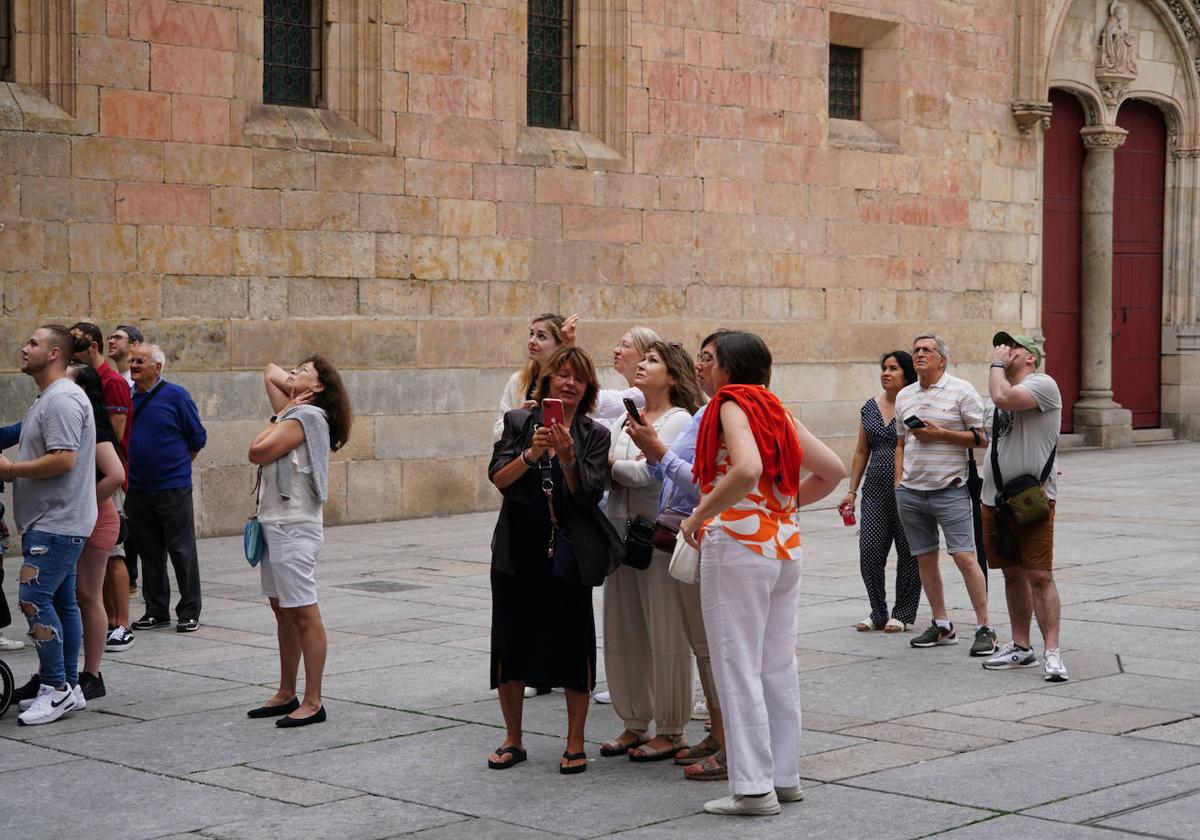 Algunos turistas, frente a la fachada de la Universidad, en un día despejado.