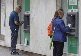 Dos salmantinos sacando dinero de cajeros automáticos.