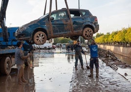 Operarios rescatan un coche atrapado por el agua.