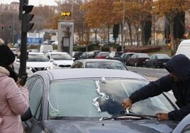 Un hombre retira la escarcha de la luna de un coche estacionado en una calle de Salamanca.