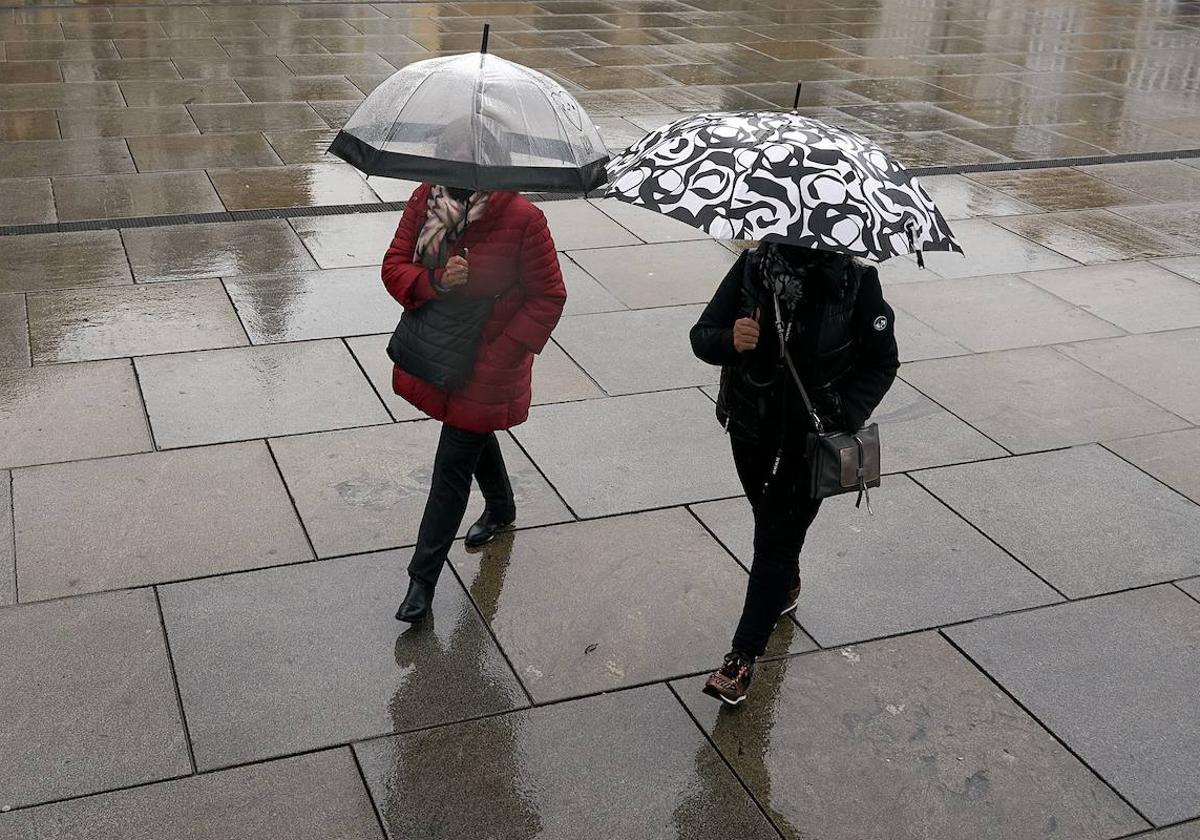 Dos personas se refugian con un paraguas de la lluvia.