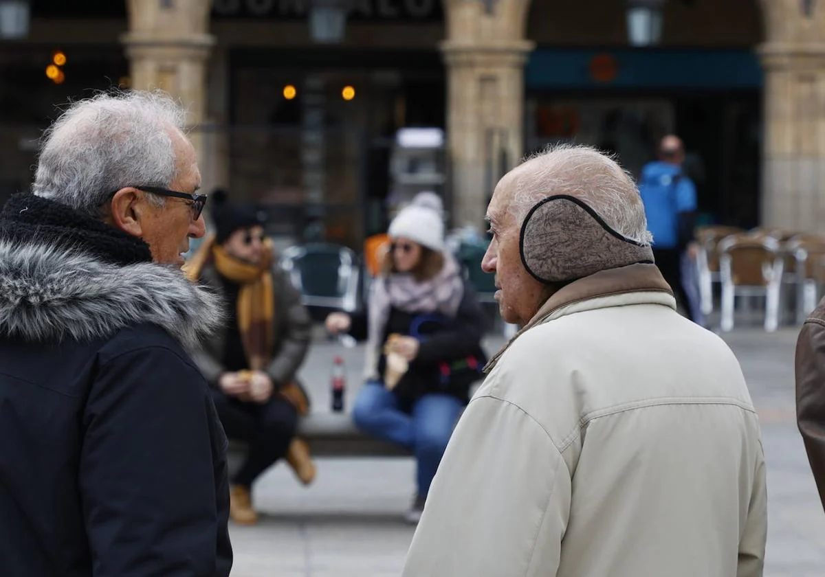 Dos salmantinos, en la Plaza Mayor, en un día de frío en Salamanca.