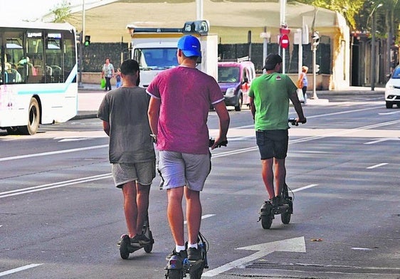 Tres hombres circulan en paralelo y sin cascos con patinetes eléctricos por la avenida de María Auxiliadora.