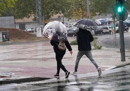 Dos salmantinos se resguardan de la lluvia.