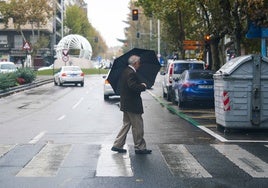 Un hombre cruzando la calle con un paraguas.