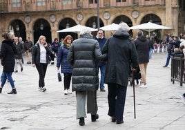 Una pareja de mayores paseando por la Plaza Mayor.