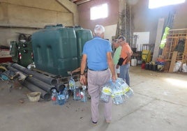 Varios vecinos recogen agua en los depósitos instalados en la nave de Cantalpino.