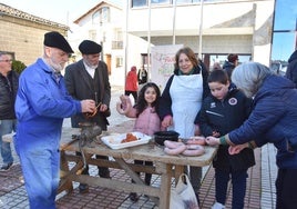 Dos niños aprenden la labor de enfusar y atar los chorizos